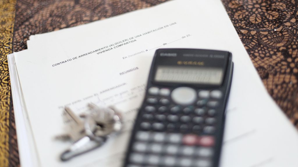 Una calculadora y unas llaves sobre un contrato de arrendamiento de una habitación en una vivienda compartida