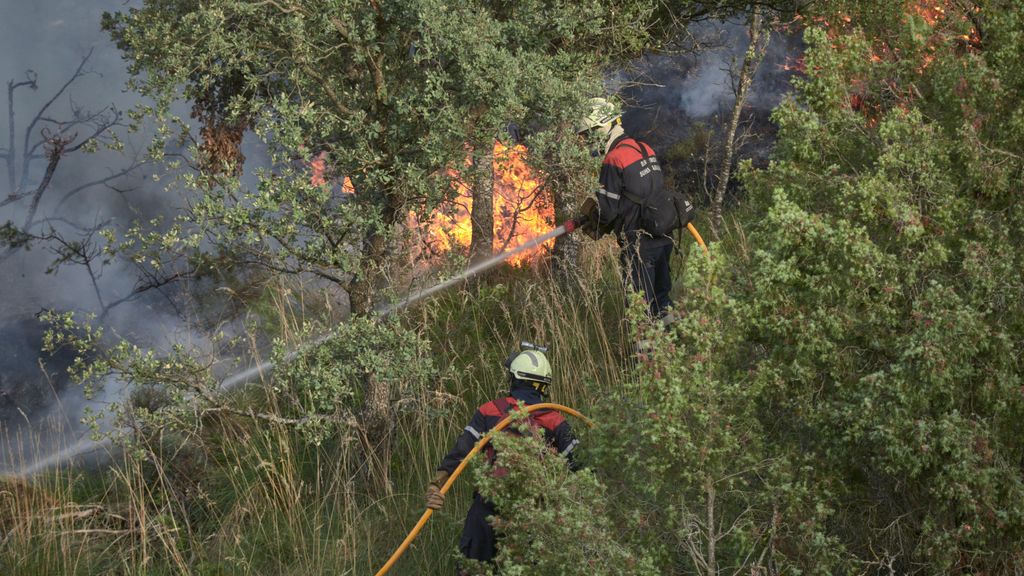 Dos bomberos trabajan durante la extinción de un incendio forestal