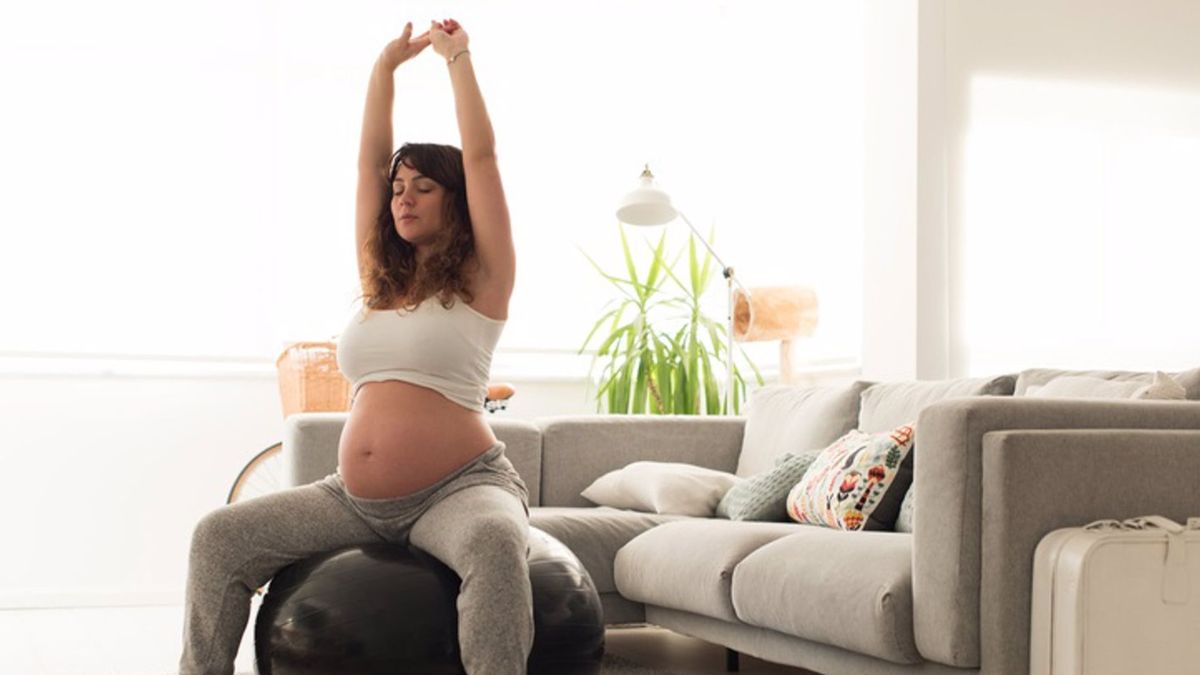 Pregnant woman doing relax exercises with a fitness pilates ball at home Pregnant woman doing relax exercises with a fitness pilates ball at home