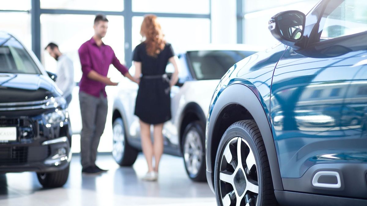 Low angle of exclusive car in a dealing salon with seller and buyer Low angle of exclusive car in a dealing salon with seller and buyer
