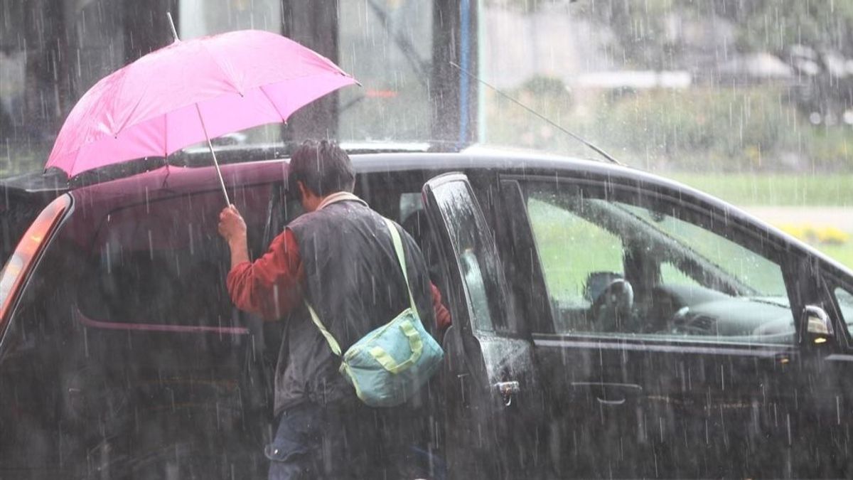 Un hombre intenta entrar en su vehículo durante una tormenta