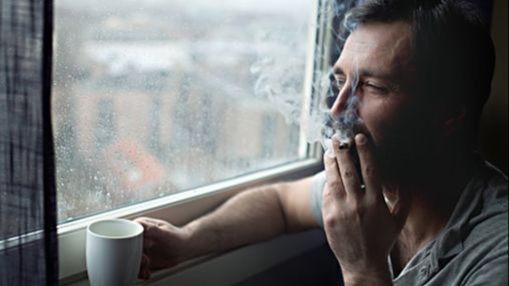 Hombre fuma en el hogar.