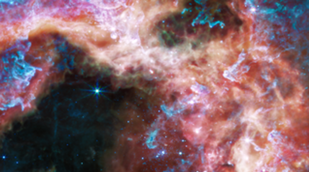 En las longitudes de onda de luz más largas capturadas por su Instrumento de infrarrojo medio (MIRI), Webb se enfoca en el área que rodea el cúmulo estelar central y revela una vista muy diferente de la Nebulosa de la Tarántula