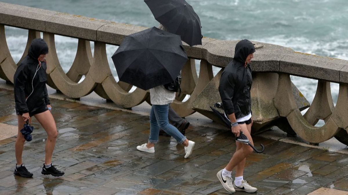 Personas caminando con paraguas por el paseo marítimo de A Coruña.