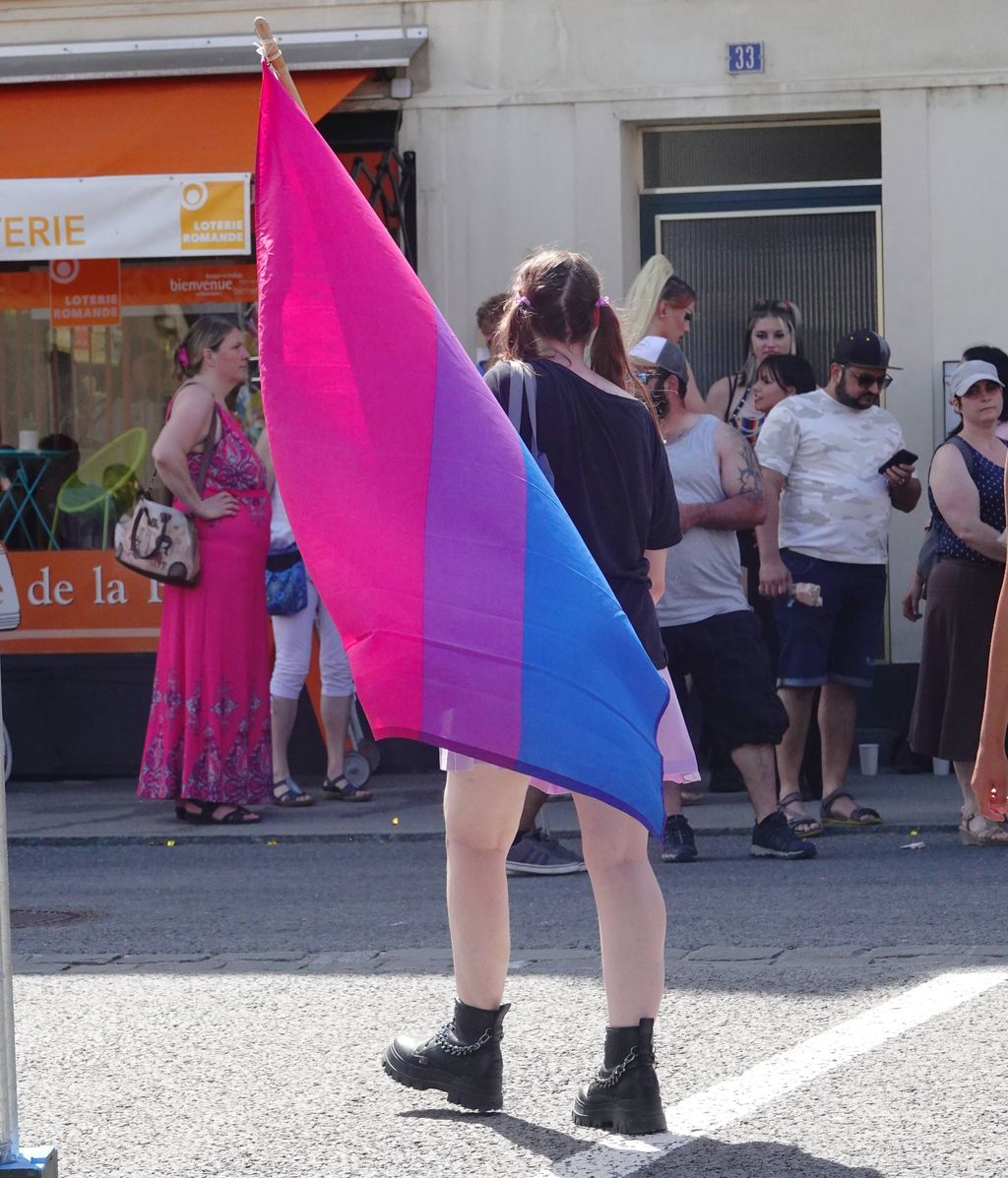 Una mujer ondea la bandera Bi en una manifestación LGTBI