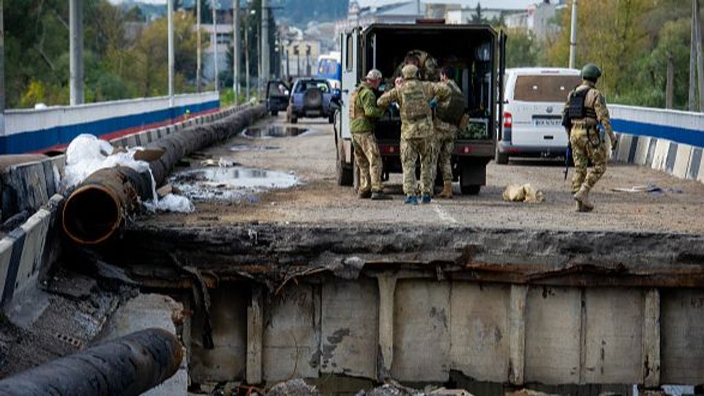 KUPIANSK, UKRAINE - SEPTEMBER 30: Ukrainian soldiers carry a wounded comrade across a heavily damaged bridge to a waiting military ambulance over the Oskil River at Kupiansk, Ukraine, on September 30, 2022. Ukraine has recaptured thousands of square miles of its northeast Kharkiv region from Russian occupation forces in recent weeks, and it continues to pour armored vehicles, artillery and rocket systems into this front to recapture all of the Donbas, while also pushing a separate offensive in the south to reclaim occupied Kherson and Crimea. (Photo by Scott Peterson/Getty Images)