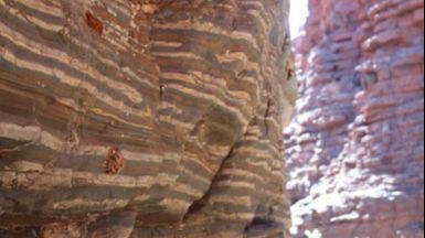 Alternancias regulares entre capas blancas, marrón rojizas y azul grisáceas en una escala de unos 10 cm, que los investigadores relacionan con el ciclo de precesión del eje de la Tierra