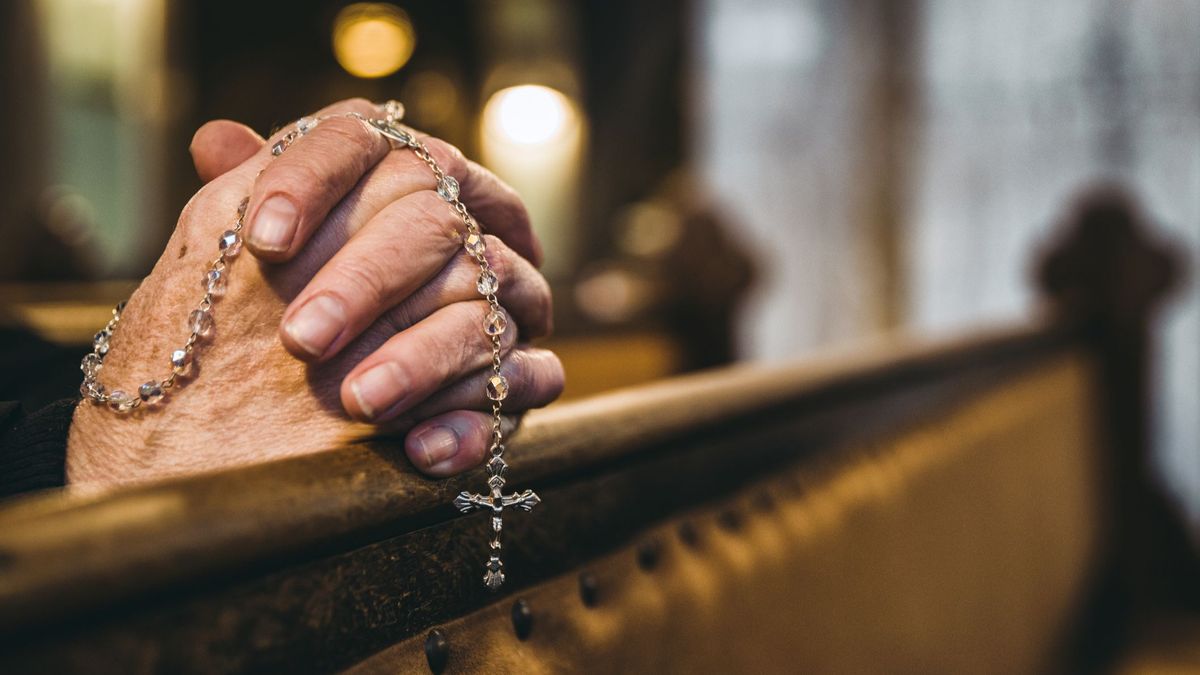 Manos rezando con rosario