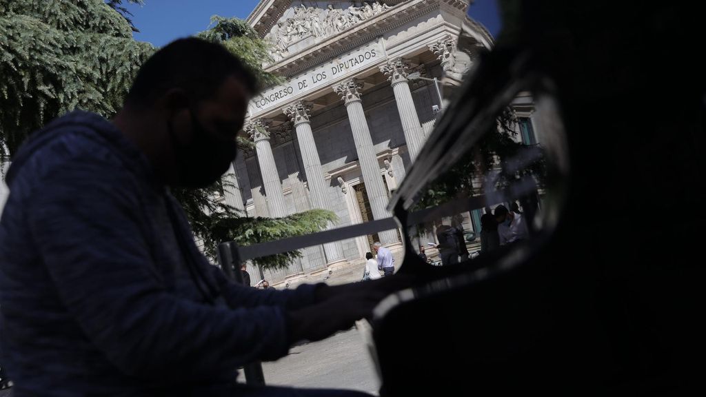 Archivo - Un hombre toca uno de los pianos de cola de la iniciativa ‘Tu ciudad se llena de pianos’, frente al Congreso de los Diputados, en octubre de 2021, en Madrid (España).