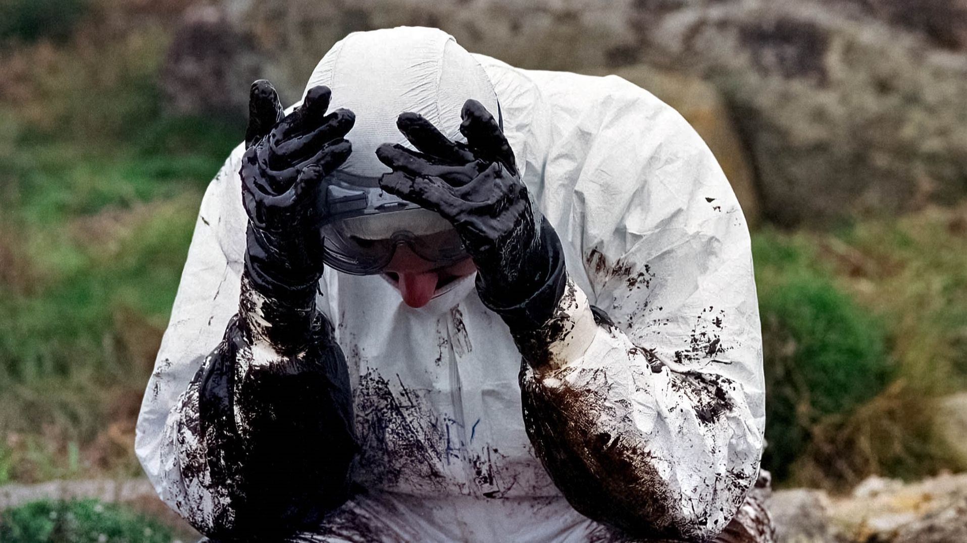 Imagen de un voluntario exhausto tras retirar el chapapote de las playas gallegas