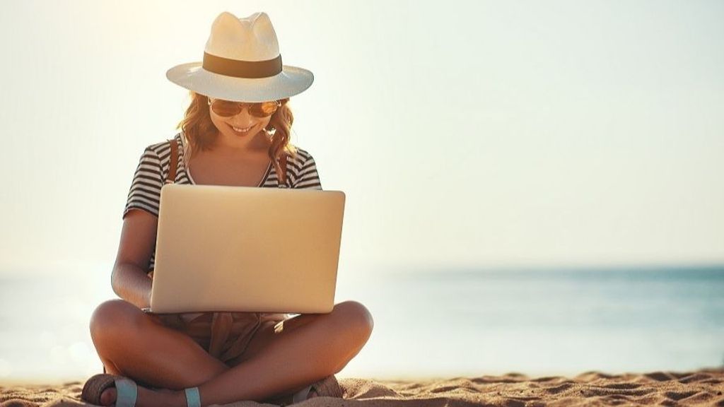 young woman working with a laptop on nature in summer beach