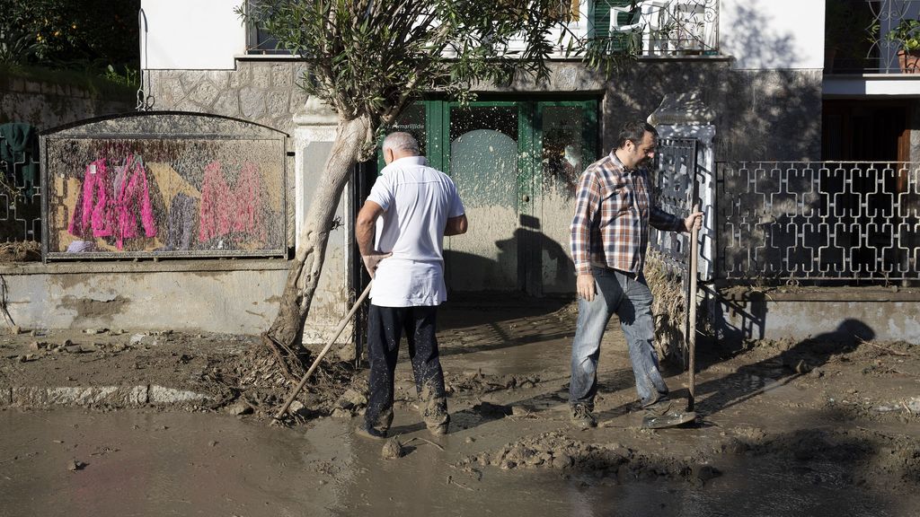 Varios vecinos de la isla de Ischia intentan limpiar sus casas del fango.