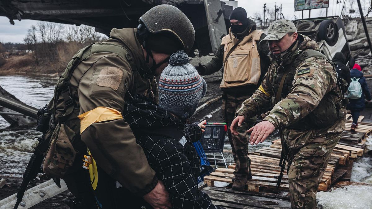 Archivo - Unos soldados ayudan a cruzar el río a un niño, a 7 de marzo de 2022, en Irpin (Ucrania).