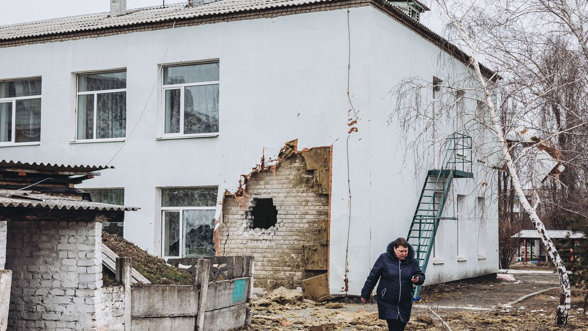 na mujer camina frente a la guardería donde hoy ha impactado un proyectil, a 17 de febrero de 2022, en Stanitsa Luganska, Oblast de Lugansk