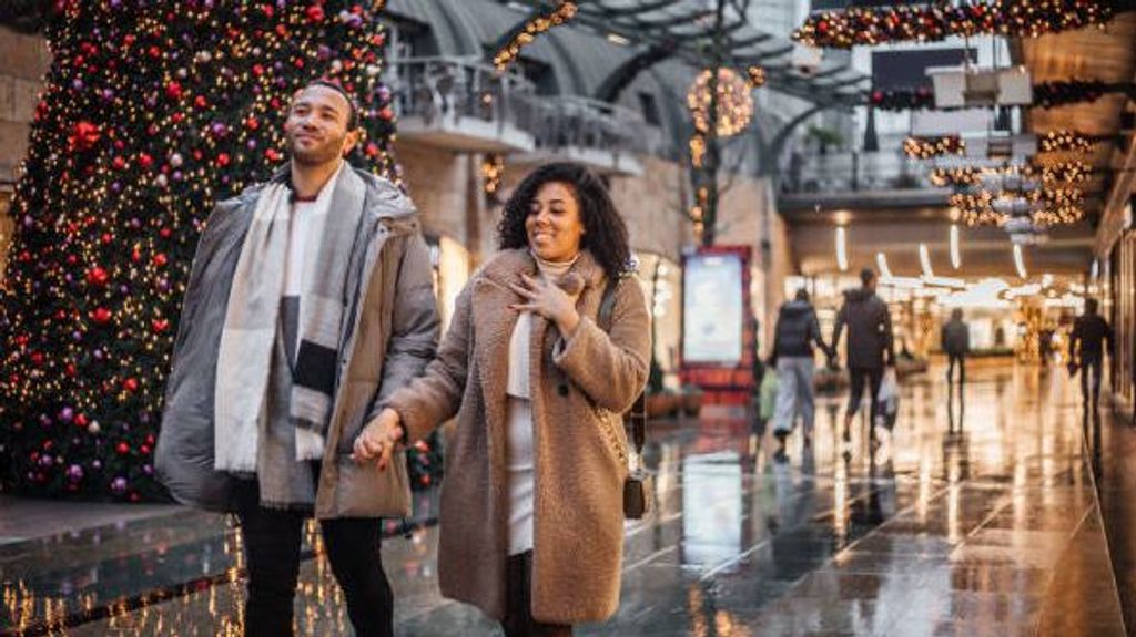 Pareja hace compras de navidad en un centro comercial.