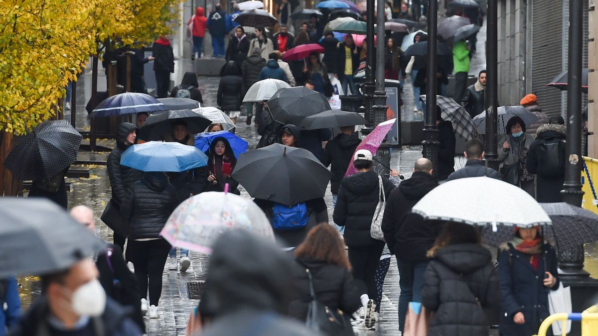 Personas caminan por la calle con paraguas