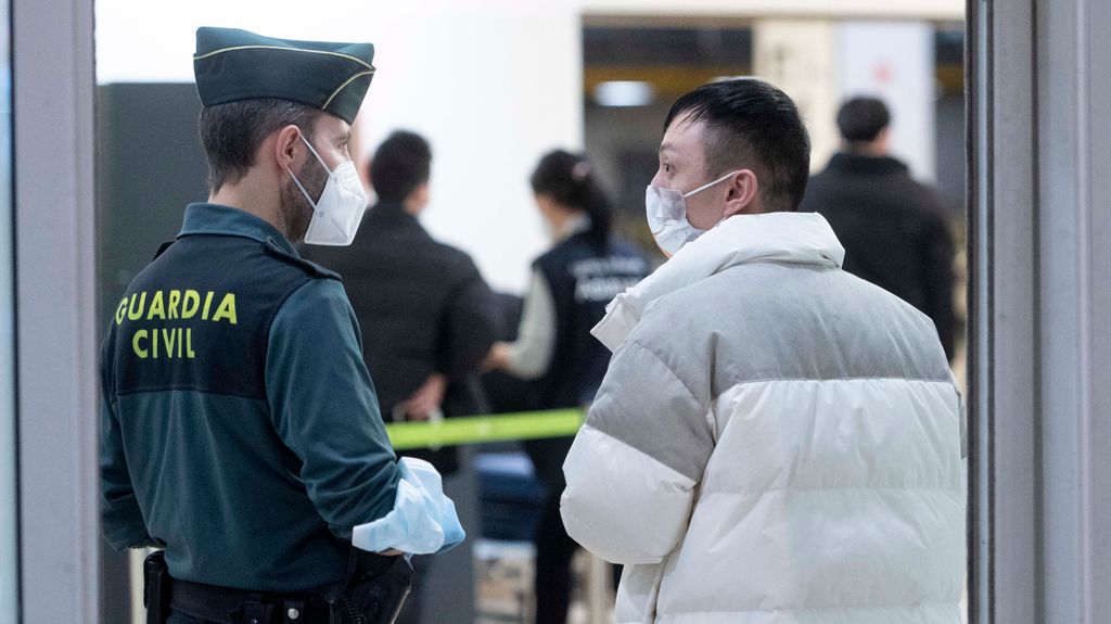 Un agente de Guradia Civil con un pasajero que llega al aeropuerto Adolfo Suárez Madrid-Barajas procedente de un vuelo de Chongqing (China), a 3 de enero de 2023