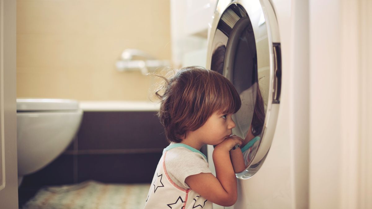 Imagen de archivo de una niña asomándose a una lavadora