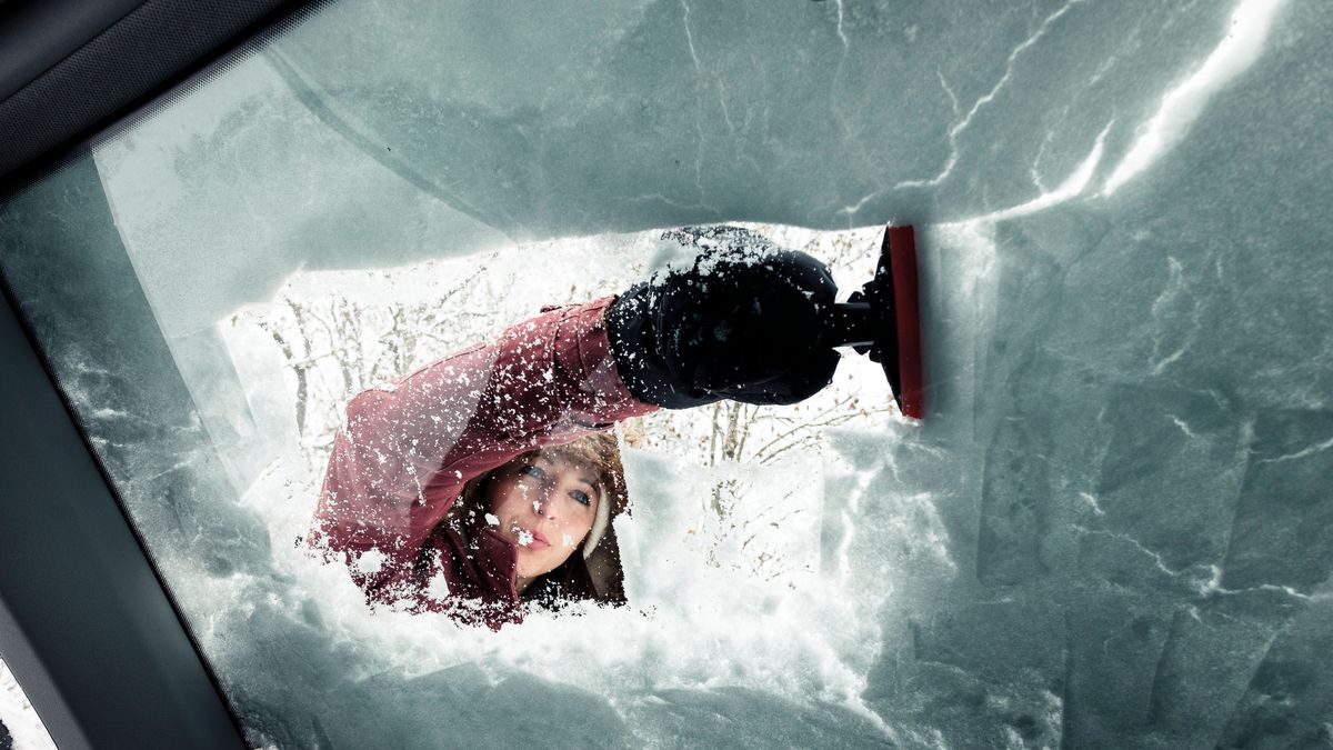 Imagen de archivo de una mujer quitan el hielo del parabrisas del coche
