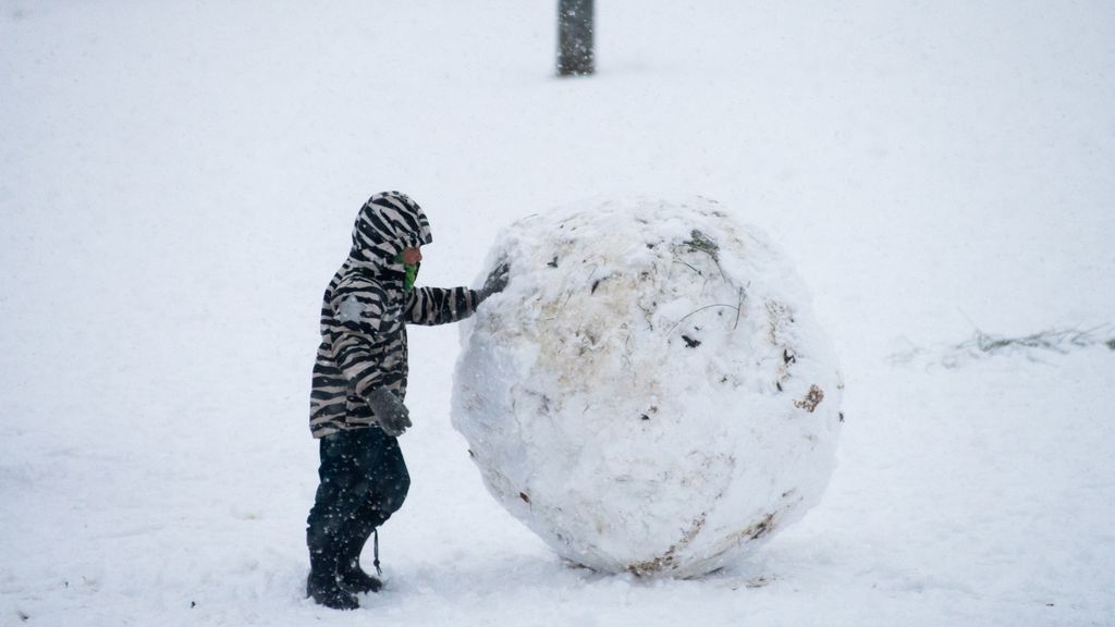 Un niño hace una gran bola de nieve