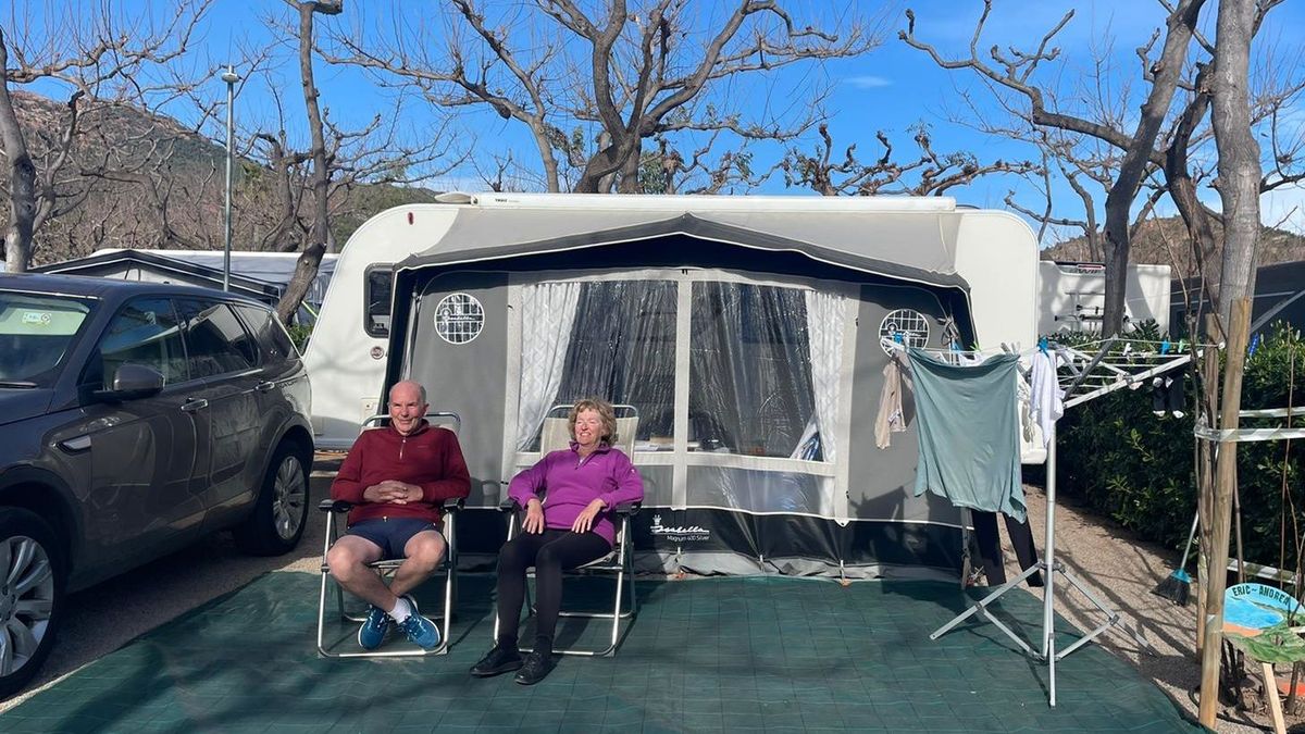 Una pareja de turistas jubilados europeos disfruta del sol frente a su caravana Una pareja de turistas jubilados europeos disfruta del sol frente a su caravana