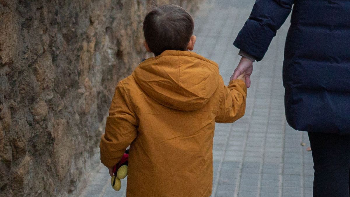 Un menor camino de la mano de su madre. Un menor camino de la mano de su madre.