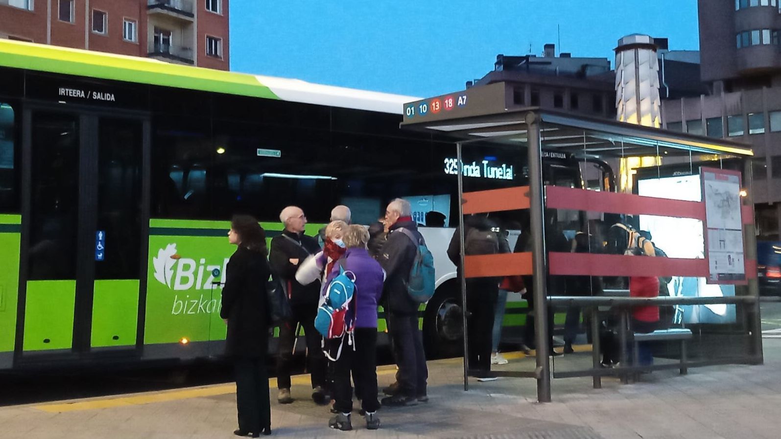 Varias personas esperan junto a uno de los vehículos de Bizkaibus