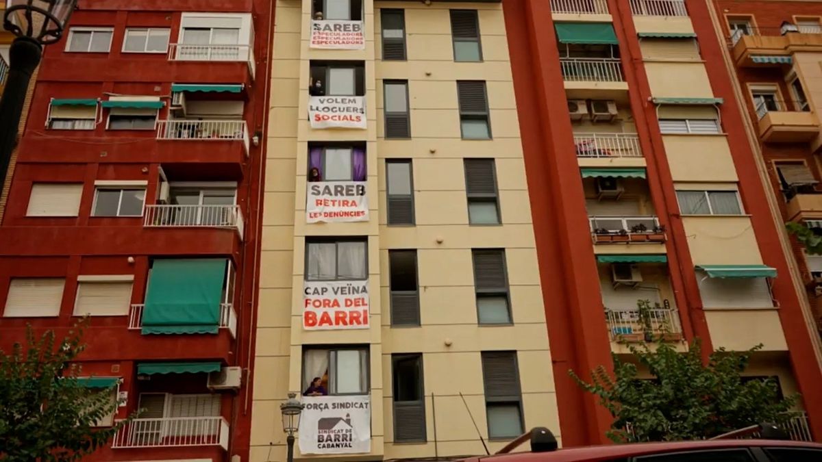 Bloque de viviendas en Barcelona con carteles reclamando más viviendas sociales en alquiler y contra la especulación inmobiliaria