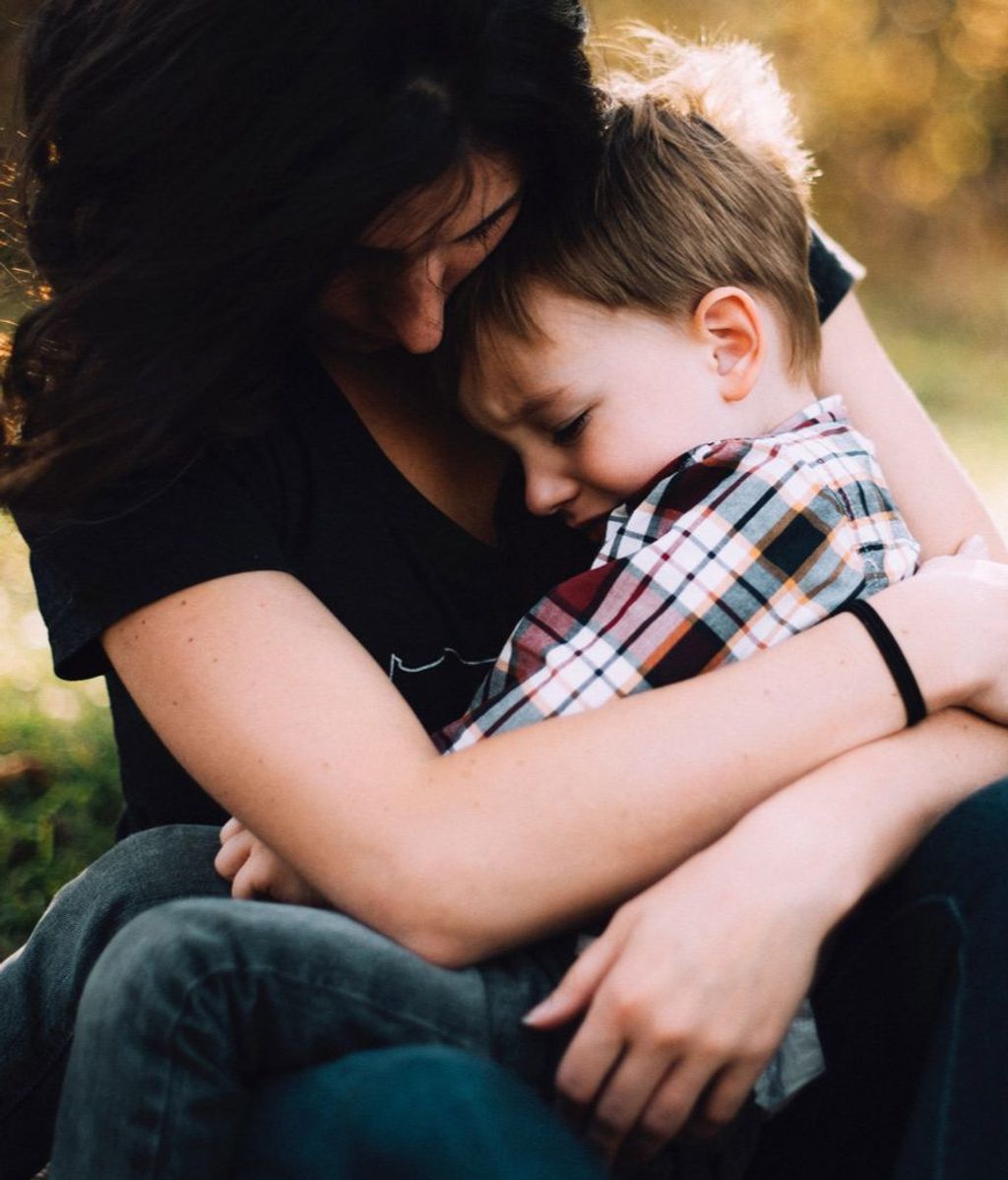 Una mujer, consolando a un niño / Foto de archivo