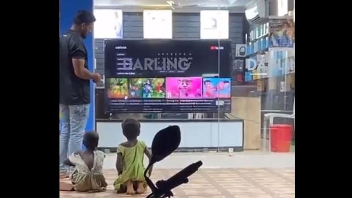 dos niños sin hogar se sientan frente a una televisión de la tienda 'Darling Electronics' localizada en Chennai, capital de Tamil Nadu,