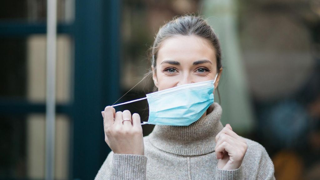 Archivo - Mujer quitándose la mascarilla.