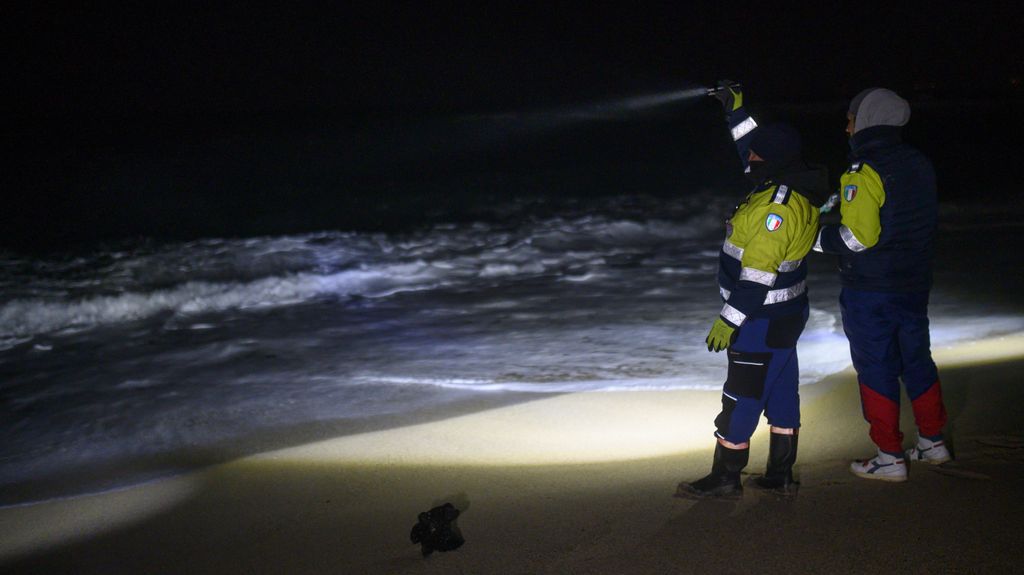 Dos miembros de la Protección Civil italiana buscan aún supervivientes en la playa de Cutro, en Calabria.
