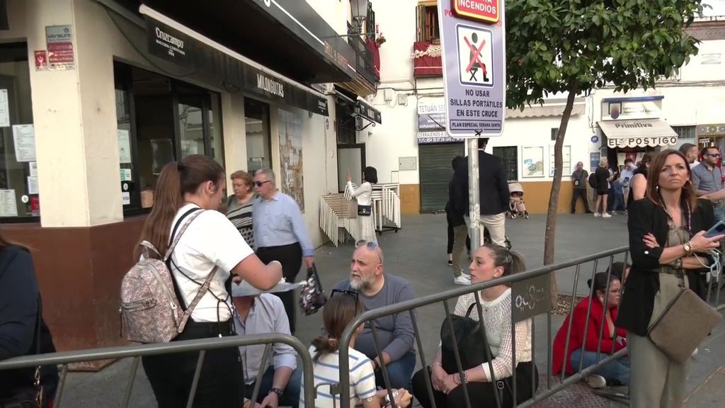 Vecinos en sillas portátiles en un lugar donde están prohibidas durante el paso de las procesiones