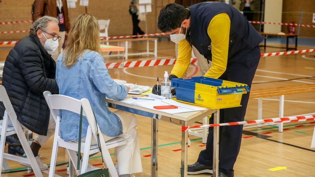 Un cartero deposita en una mesa electoral votos enviados por correo