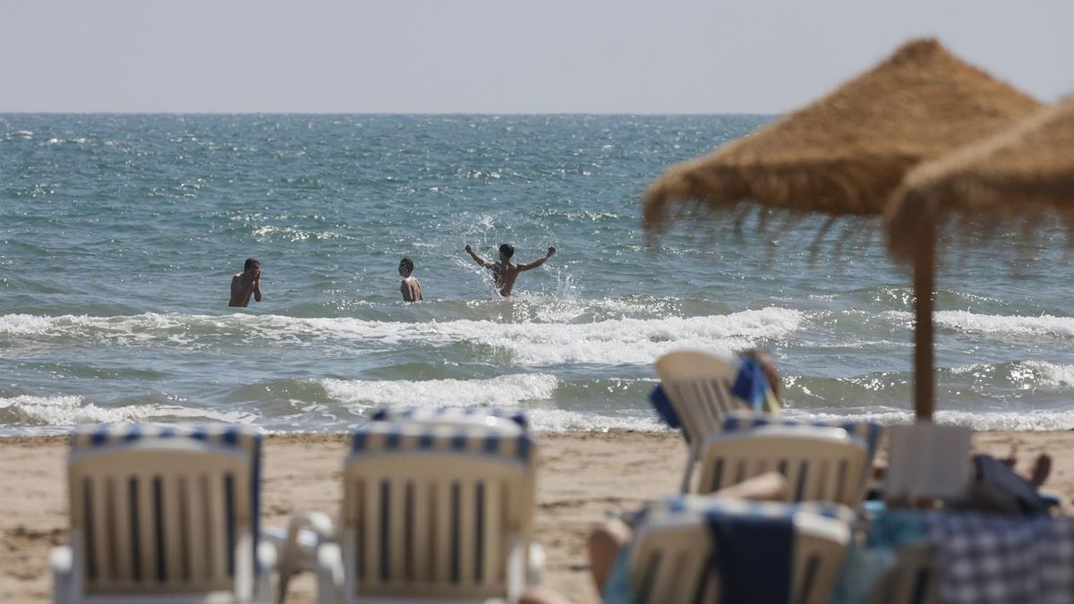 Varias personas se bañan en la playa de la Malvarrosa, en Valencia