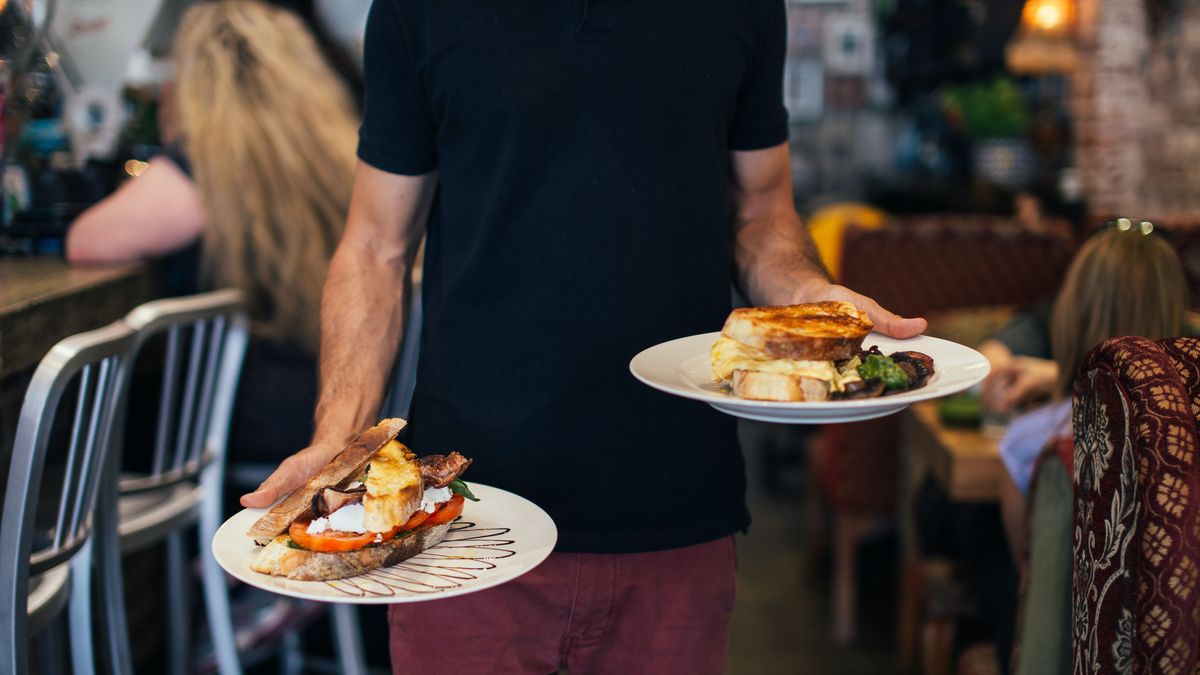 Un camarero lleva los platos a una mesa