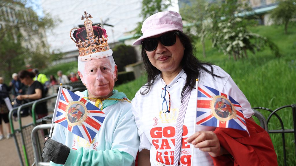 Una persona con una máscara de Carlos III celebra la coronación del nuevo rey de Inglaterra por las calles de Londres