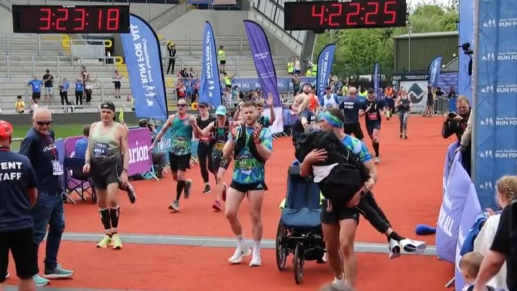 Un entrenador de rugby cruza la meta de la maratón de Leeds con su excompañero enfermo de ELA en brazos