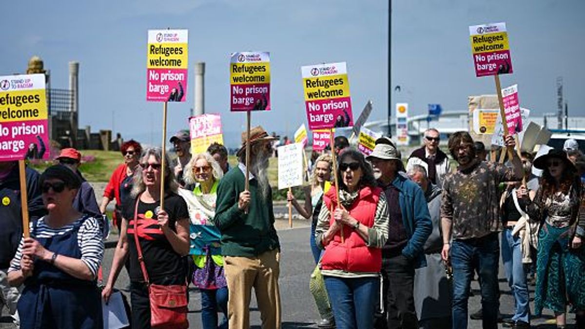 Manifestantes marchan en el puerto de Portland durante una manifestación contra los planes del gobierno del Reino Unido de albergar a 500 inmigrantes en una barcaza frente a la costa de Dorset el 13 de mayo de 2023 en Portland, Inglaterra