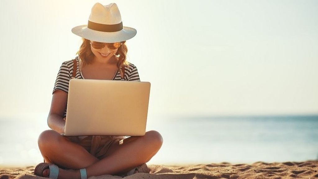 young woman working with a laptop on nature in summer beach