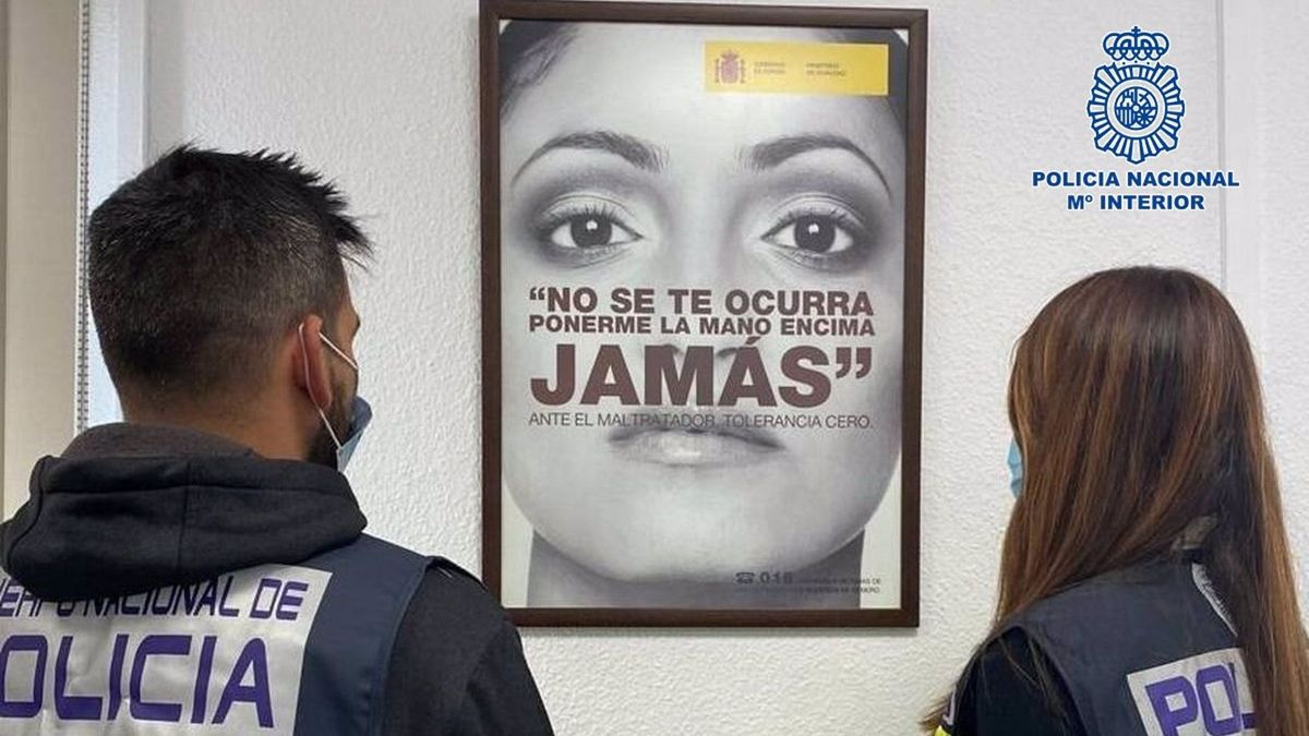 Agentes de la Policía Nacional de Málaga delante de un cartel contra el maltrato