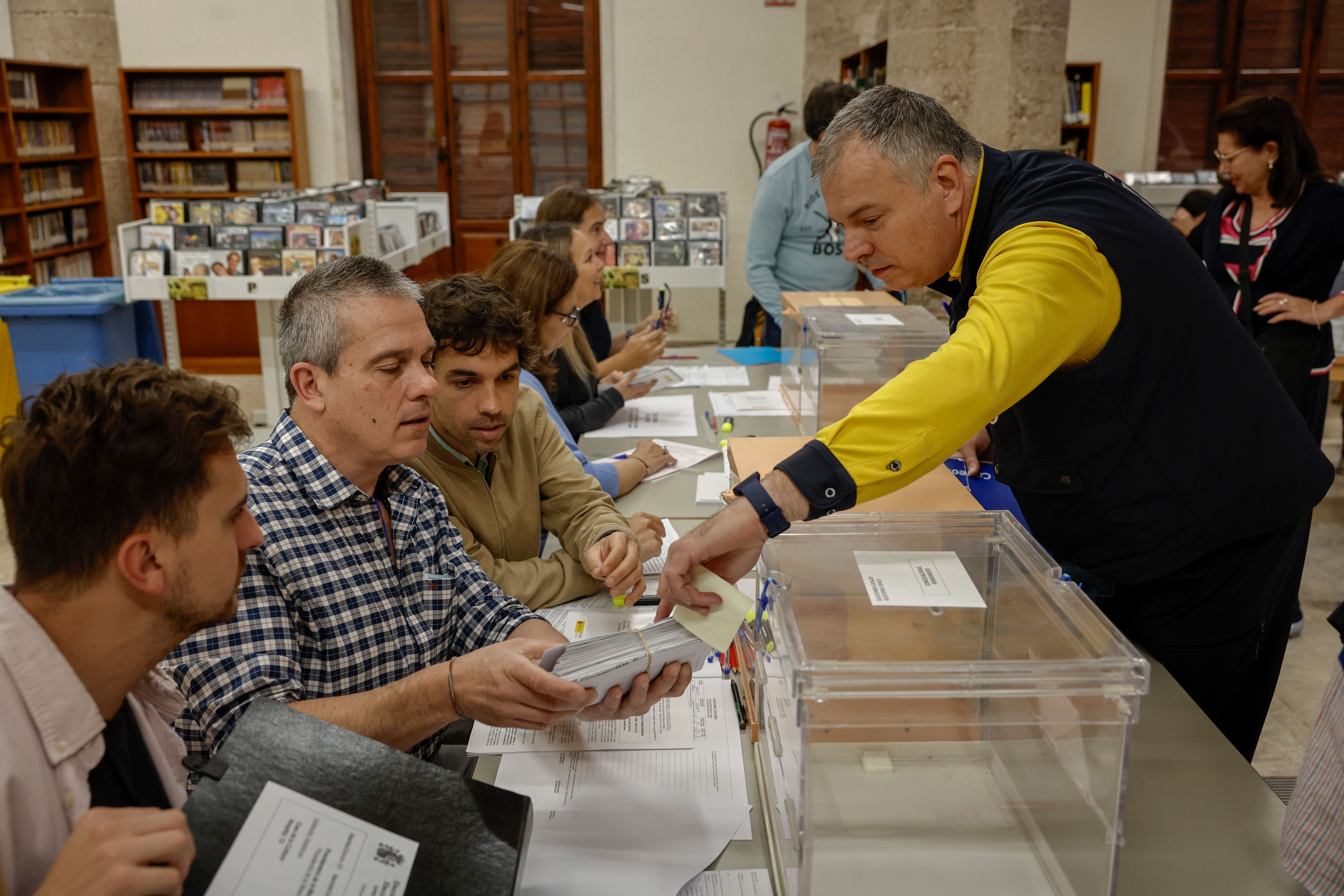 Un cartero entrega los votos emitidos por correo en una mesa electoral de Valenci