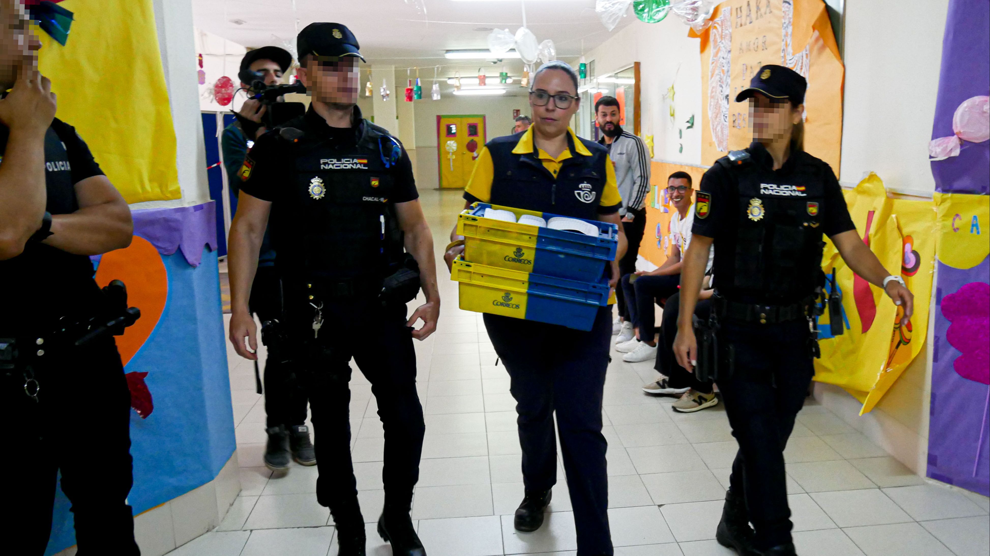 Dispositivo de Seguridad en Colegio León Solá de Melilla en el que varios agentes escoltan a la funcionaria de Correos a la mesa electoral para entregar los votos por correo