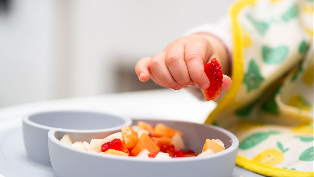 Un niño come fruta en un menú infantil