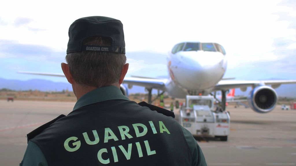 Archivo - Un agente de la Guardia Civil, de espaldas, en la pista de un aeropuerto con un avión al fondo.