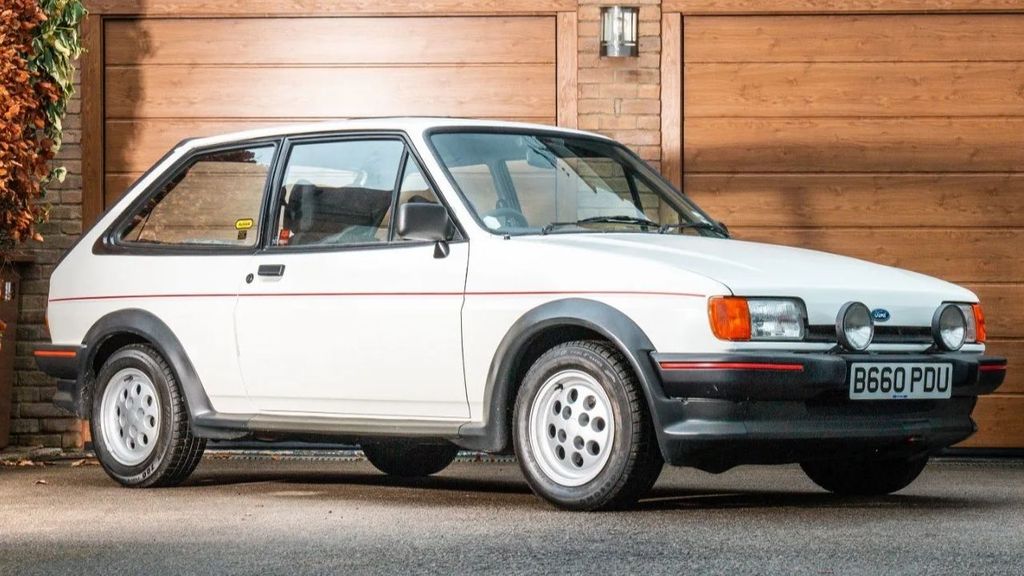 Sí, es un Ford Fiesta Blanco. Aunque nació en los 70, fue en la década de los 80 que el coche se consolidó como el turismo juvenil más demandado.