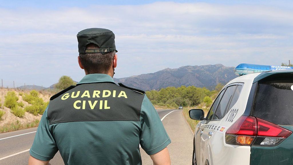 Archivo - Un agente de la Guardia Civil junto a un vehículo en una carretera.  (Foto de archivo).