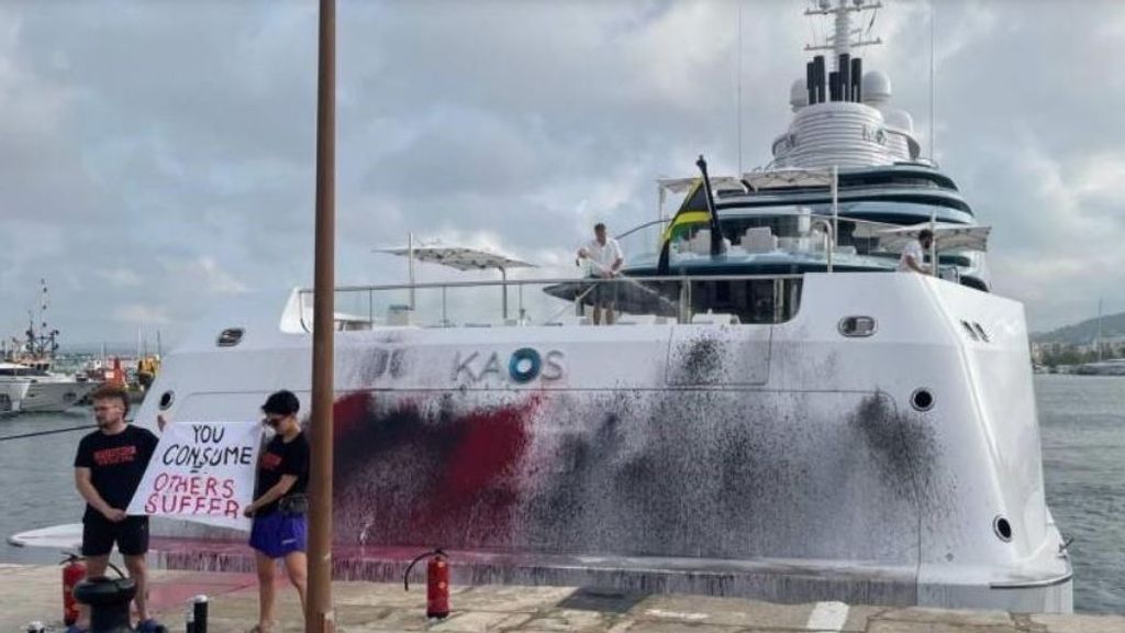 Dos activistas pintan el casco de un super yate en el puerto de Ibiza