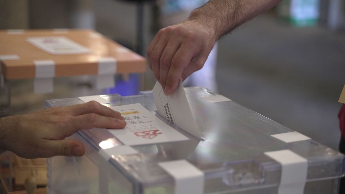 Una persona deposita su voto en una urna para las elecciones generales de España