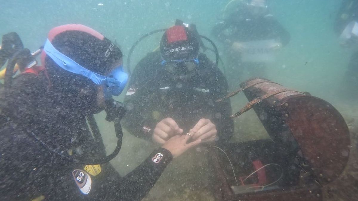 César colocándole el anillo bajo el mar a Gema, su novia.